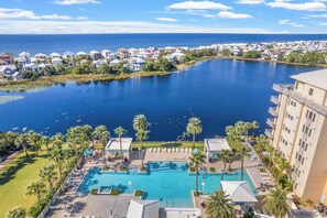 Een resort met een groot zwembad, palmbomen en uitzicht op de oceaan.