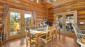 A log cabin with a wooden dining table, chairs, and a chandelier. - Beaver Creek Luxury Lodge (Custer)