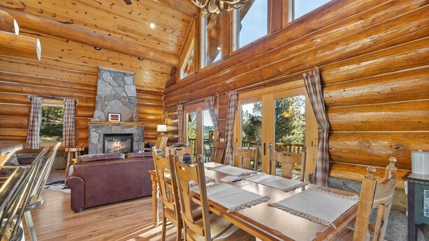 A log cabin interior with a fireplace, dining table, and chairs. - Beaver Creek Luxury Lodge (Custer)