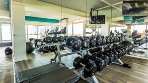 A gym with a treadmill, a mirror, and a rack of dumbbells. - GSR - Grande Caribbean (Pattaya)