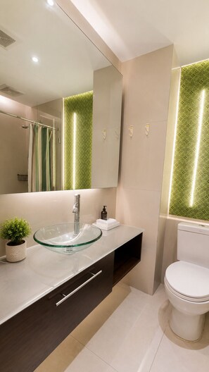 A modern bathroom with a glass sink, a toilet, and a mirror. - GSR - Grande Caribbean (Pattaya)