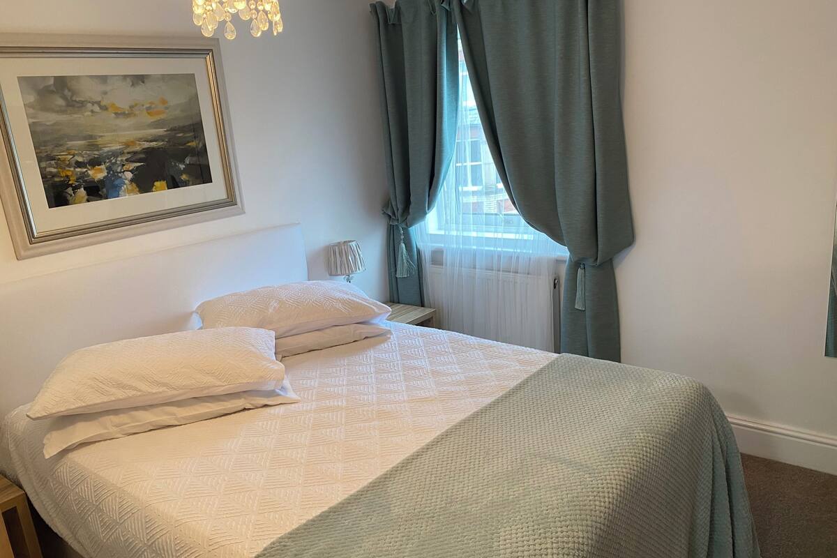 A neatly made bed with a patterned bedspread, a bedside lamp, and a framed picture on the wall.