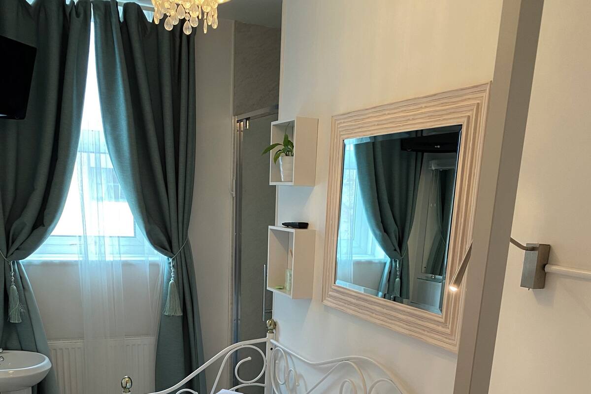 A neatly arranged bedroom with a bed, bedside table, and a mirror.