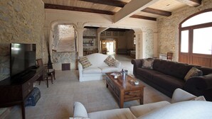 Un amplio salón con paredes de piedra, techo de madera y un ventanal grande.