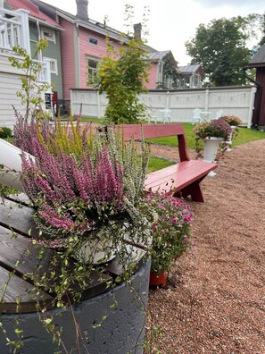 Sit and unwind in a serene garden setting, surrounded by vibrant flowers and a peaceful residential backdrop.
