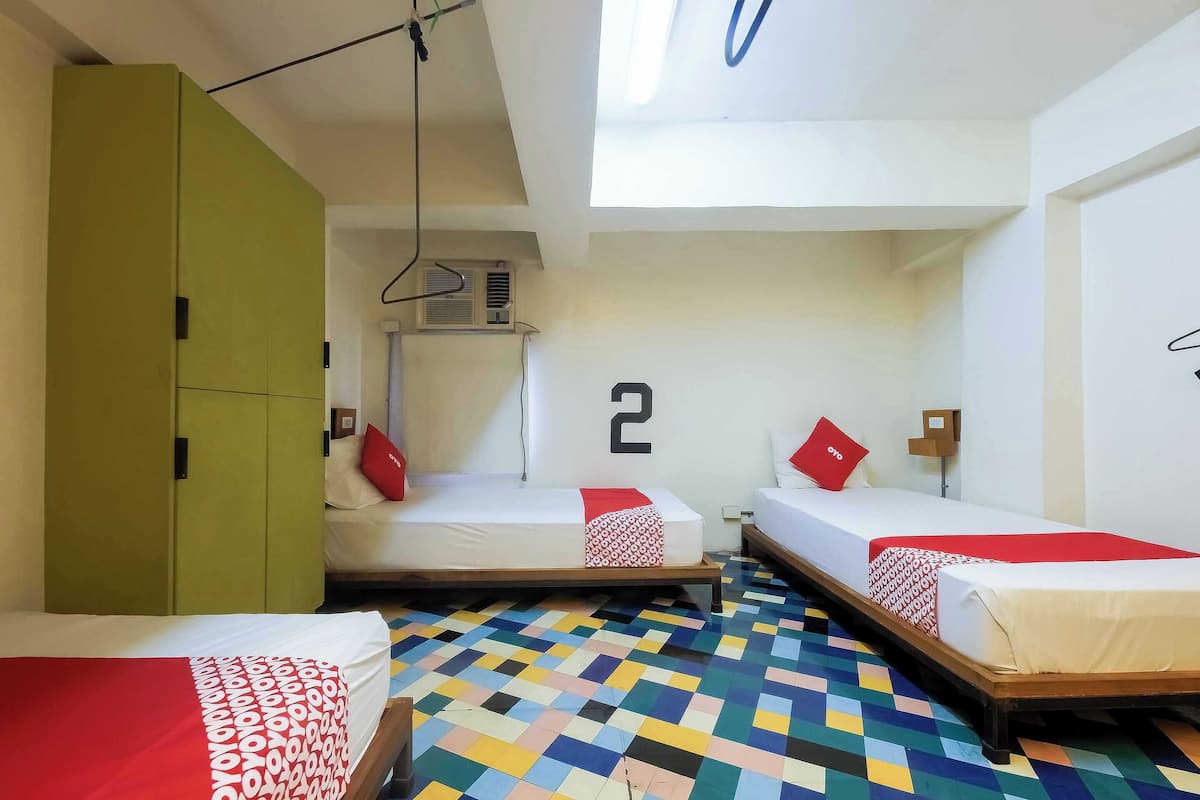 Een kamer met twee bedden, een groene kast en een vloer met kleur.