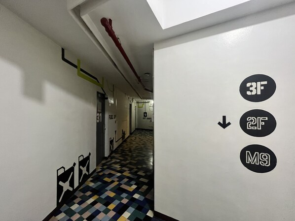 A hallway with a checkered floor, directional signs, and a door labeled '31'. - Junction Hostel Poblacion Makati Avenue (Makati)