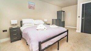 A bedroom with a bed, bedside tables, a wardrobe, and a door.