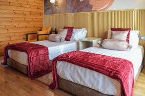 A hotel room with two beds, wooden paneling on the walls, and a mural.