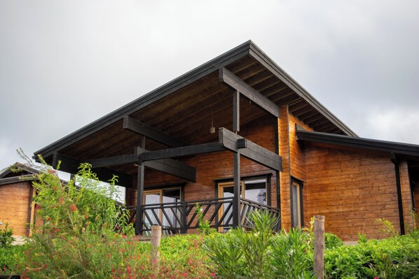 A modern wooden building with a sloped roof and a balcony.