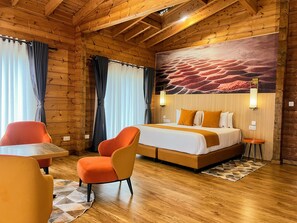 A wooden room with a bed, two chairs, a table, and a wall mural.
