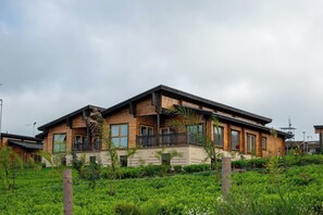 A modern two-story house with a balcony, surrounded by lush greenery. - Ridge Cabin Resort (Limuru)