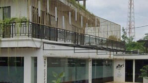 Un edificio dal design moderno, con un balcone dotato di ringhiere in metallo e piante in vaso. Sulla facciata dell'edificio è presente un cartello con la scritta 'MSP Coffee'.