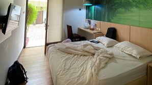 Una camera d'albergo con un letto, una scrivania, una sedia e un grande murale.