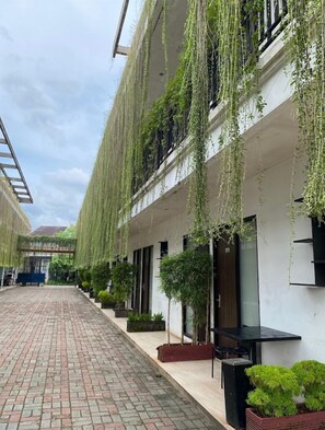 Un bâtiment orné de plantes suspendues et doté d’une cour pavée de briques.
