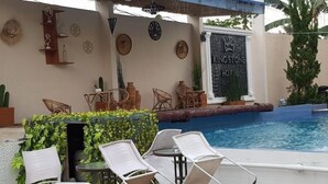 Zona piscina con lettini, un tavolino e decorazioni murali all'Hotel Kingstone.