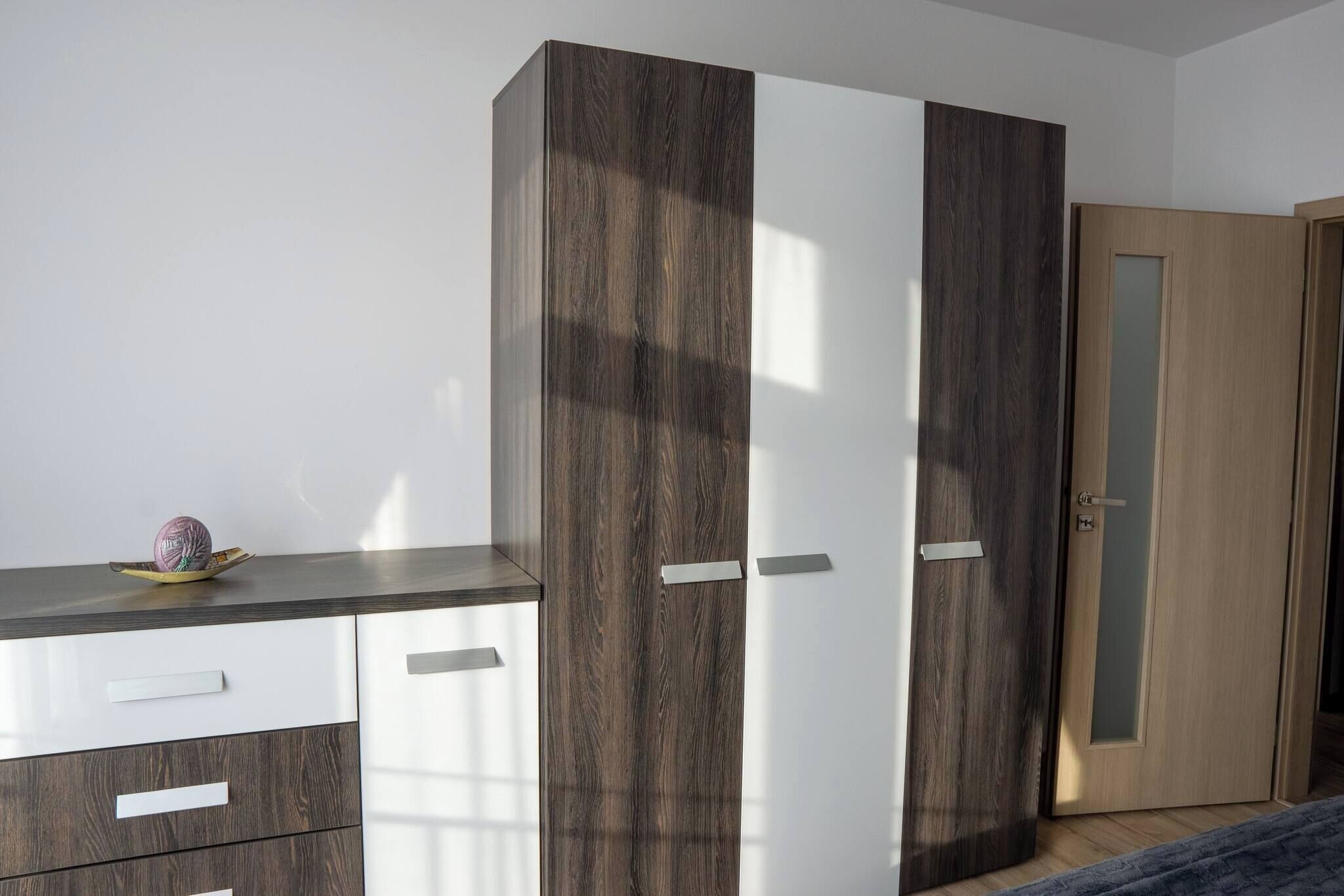 A bedroom with a bed, a wardrobe, and a dresser.