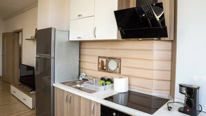 Une cuisine moderne avec des meubles blancs, un réfrigérateur en acier inoxydable, un micro-ondes noir et une machine à café.