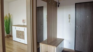Une pièce avec un meuble en bois, un miroir et une porte munie d’un téléphone et d’un interrupteur.