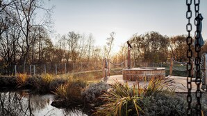 Un parc paisible avec une terrasse en bois, un petit étang et diverses plantes.