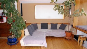A cozy room with a sectional sofa, a potted plant, and a window.