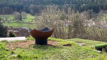 Un paysage avec une grande structure à la forme unique au premier plan, une zone herbeuse et un village en arrière-plan.