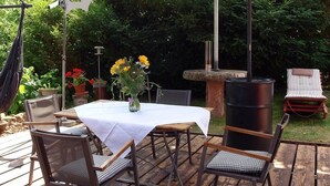 An outdoor patio with a table and chairs, a hanging chair, a barbecue grill, and a decorative fountain.