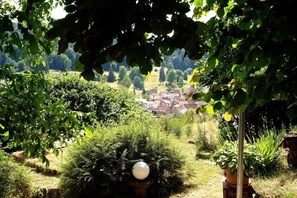 Un jardin avec un objet sphérique, une plante en pot et une vue sur un village au loin.