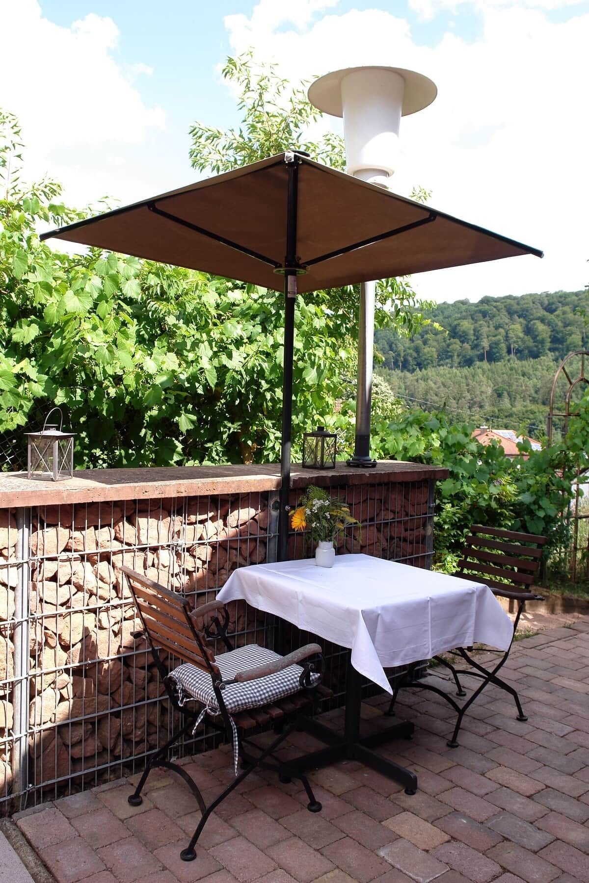 An outdoor patio with a table and chairs, a large umbrella, and a lantern.
