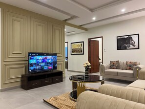 Una sala de estar con televisor, sofá y mesa de centro.