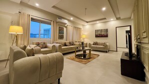 A spacious living room with a sofa set, a coffee table, and a flat-screen TV.