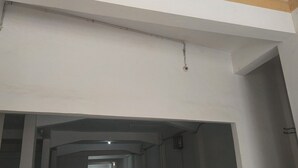 Un couloir intérieur aux murs blancs et au plafond orné de poutres apparentes.