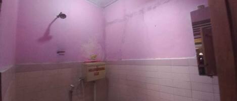 A bathroom with pink walls, a shower, and a toilet.