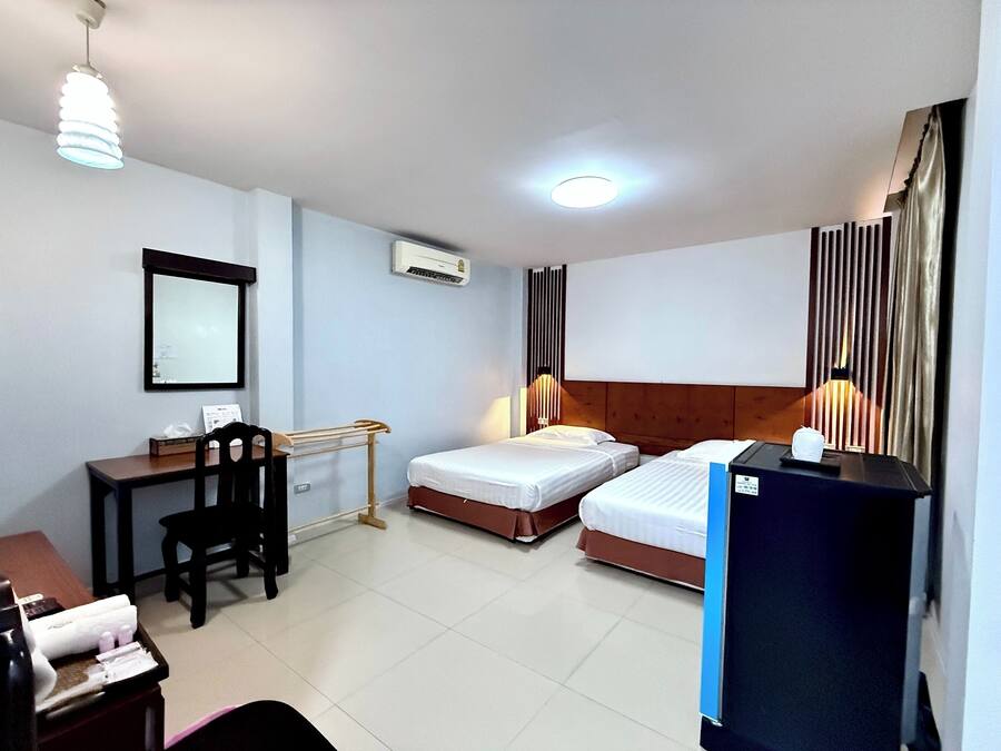 Une chambre d’hôtel avec deux lits, un bureau avec une chaise, une télévision et un mini-bar.