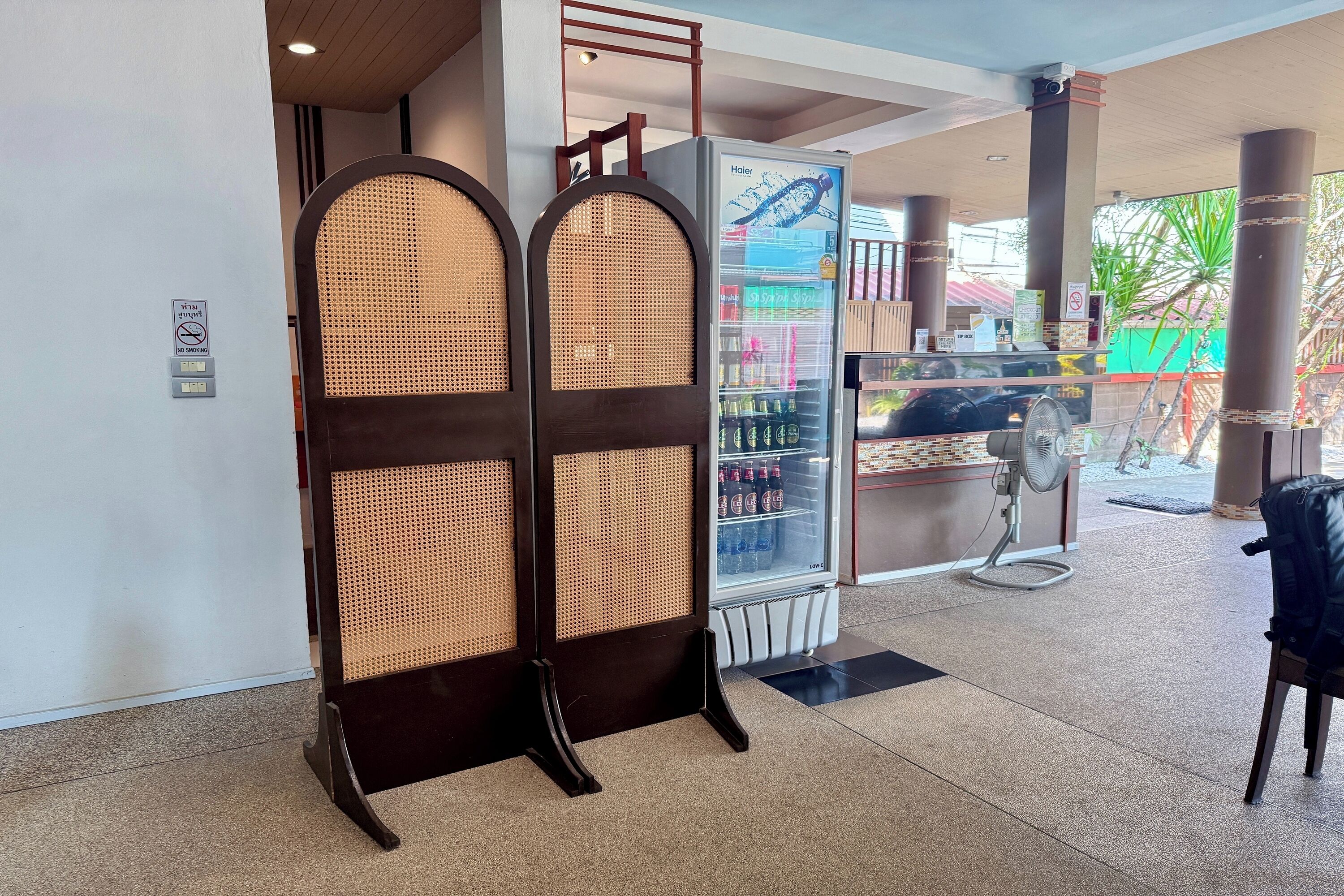 A hotel lobby with a reception desk, a vending machine, and a fan.