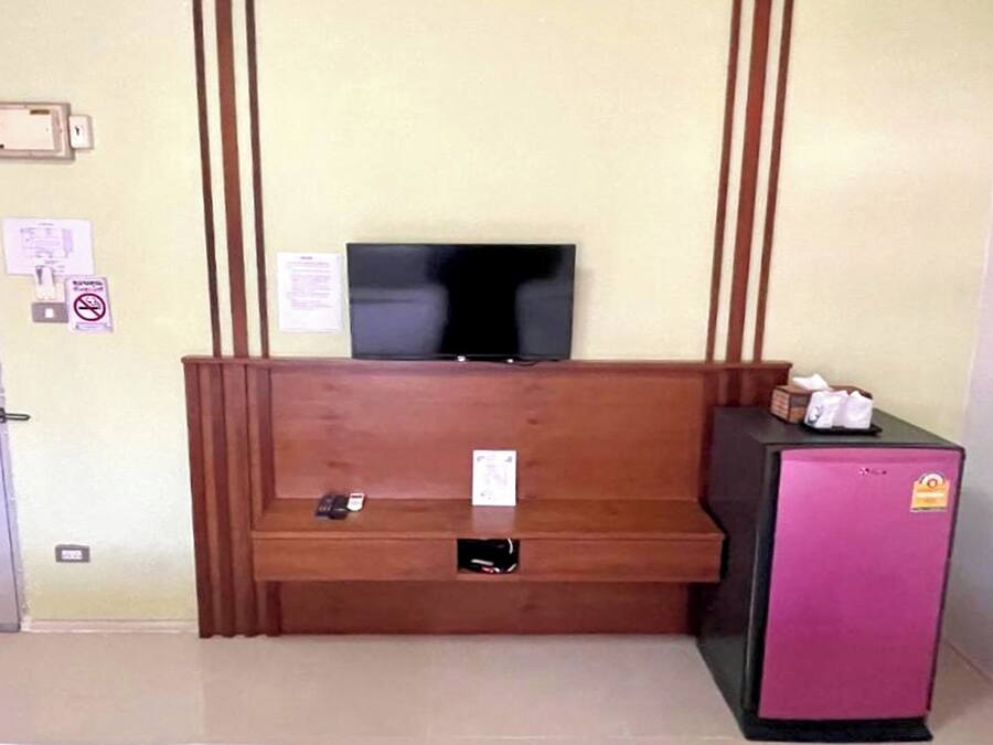 A room with a wooden bench, a television mounted on the wall, and a refrigerator.