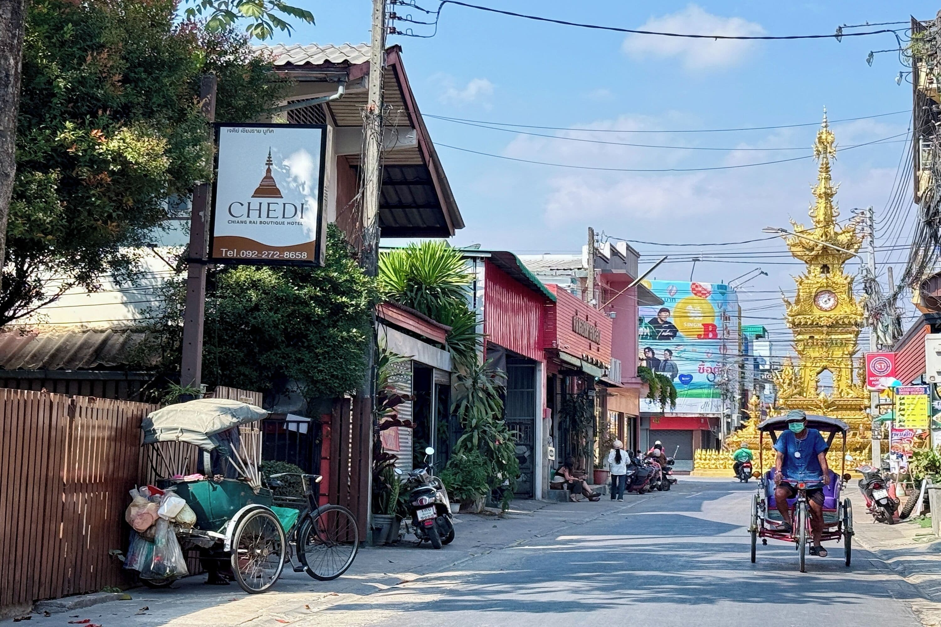 A street view with a sign for 'CHEDI' boutique hotel, a tuk-tuk, and a golden stupa in the background.