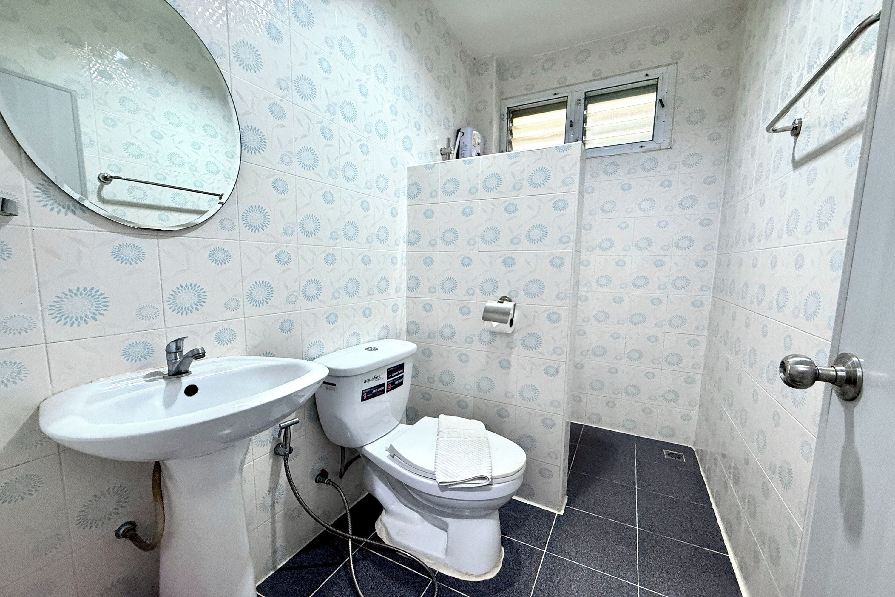 A bathroom with a white sink, toilet, and a mirror. The walls have a patterned tile design.