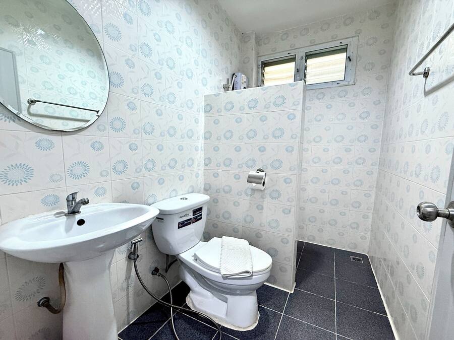 A bathroom with a white sink, toilet, and a mirror. The walls have a patterned tile design.