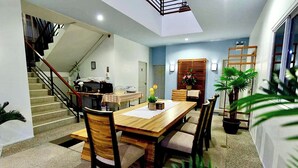 Un espace repas avec une table et des chaises en bois, un escalier et une vue sur l’extérieur.