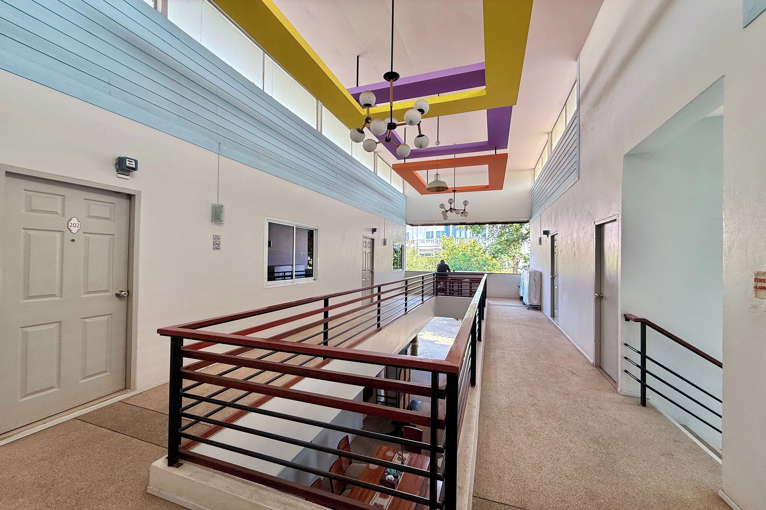 A modern hotel corridor with a staircase, a flat-screen TV, and a balcony with a view.