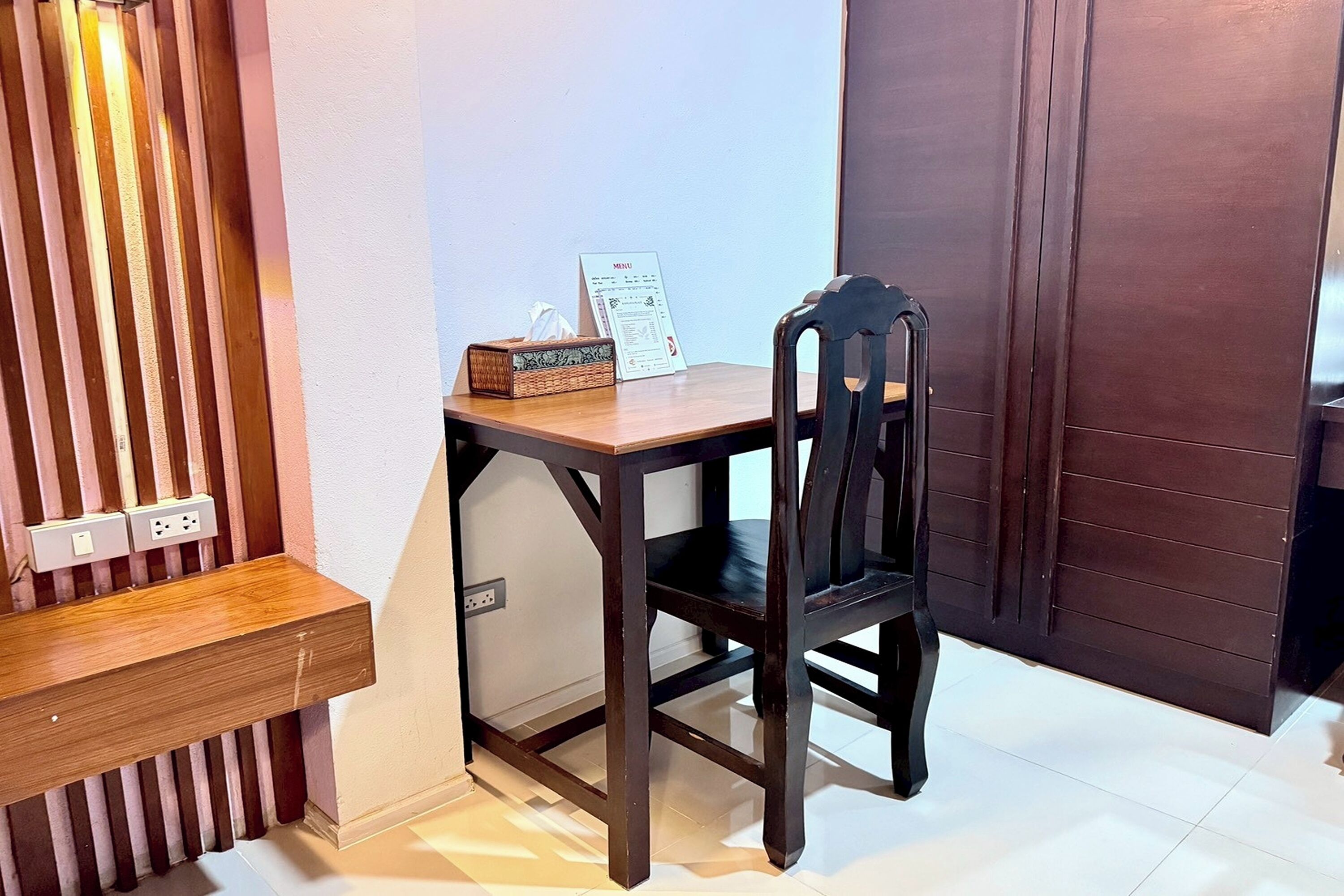 Een klein houten bureau met een stoel, een zakdoosje en een menukaart.