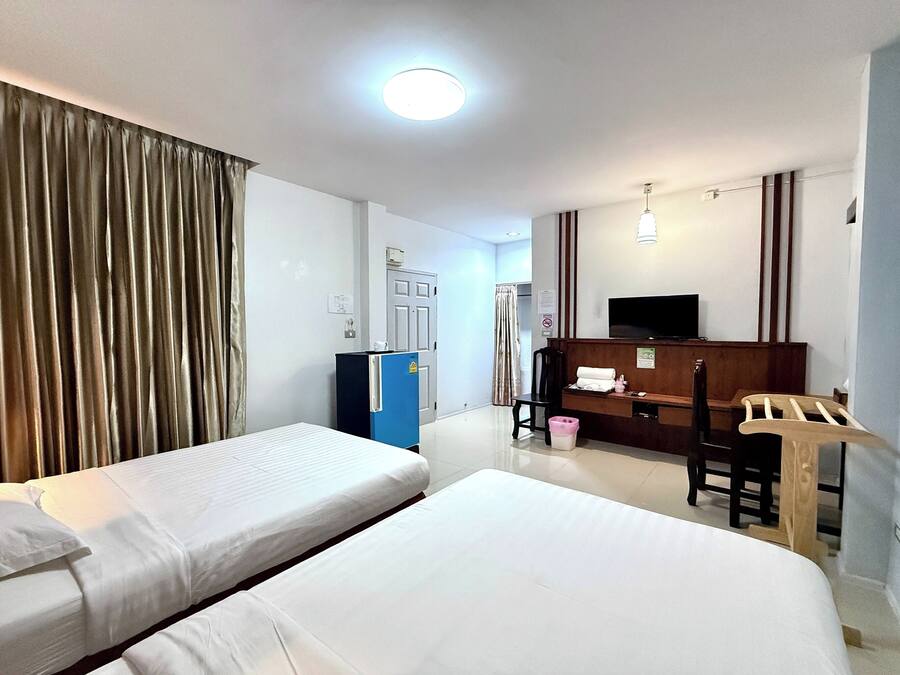 Ett hotellrum med två sängar, ett skrivbord, en stol, en TV och en minibar.
