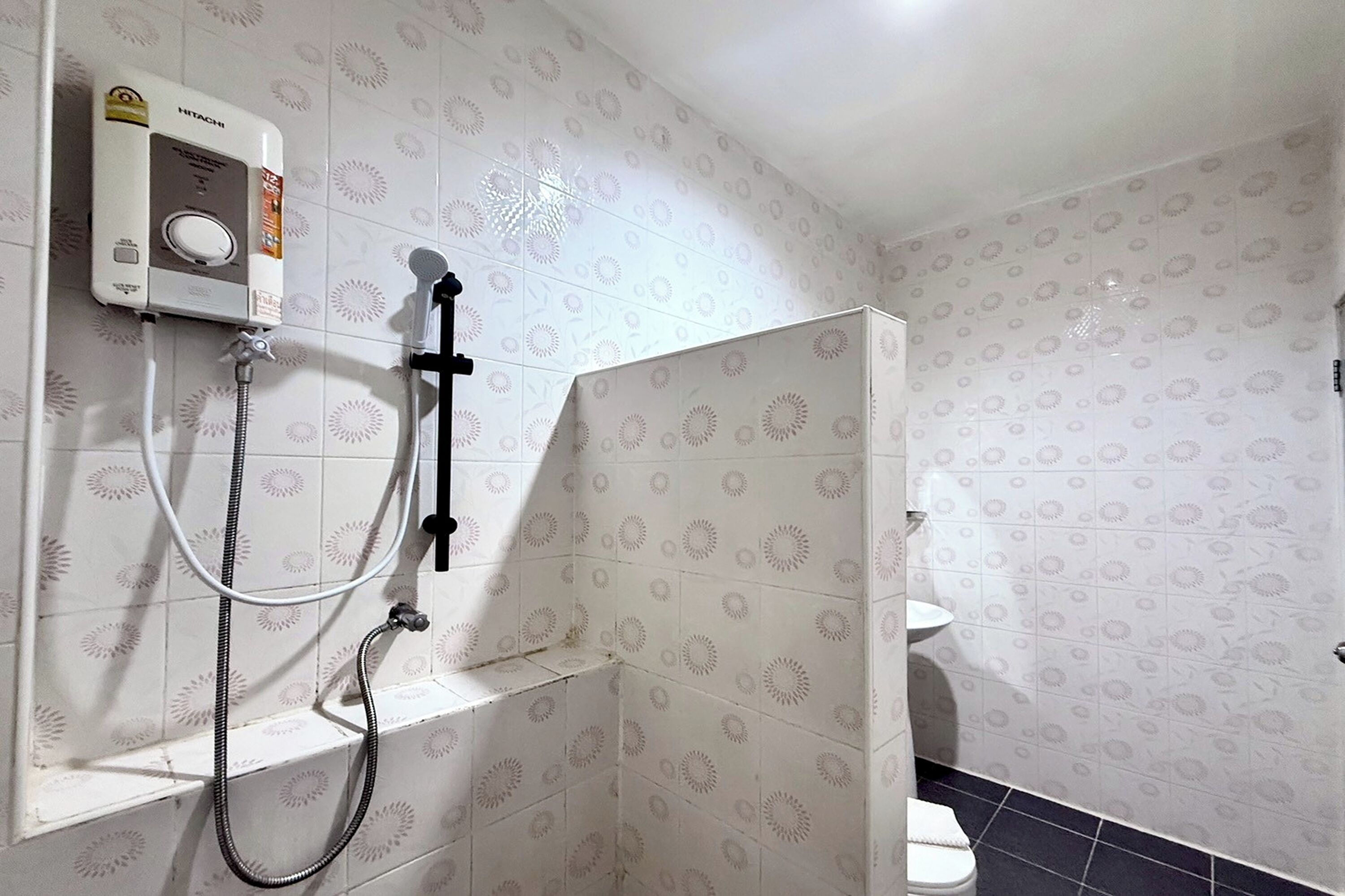 Un baño con ducha, inodoro y un calentador de pared.