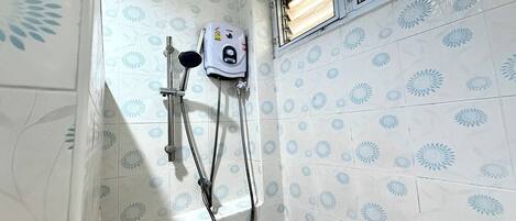 Un baño con ducha, calentador de agua y azulejos estampados.