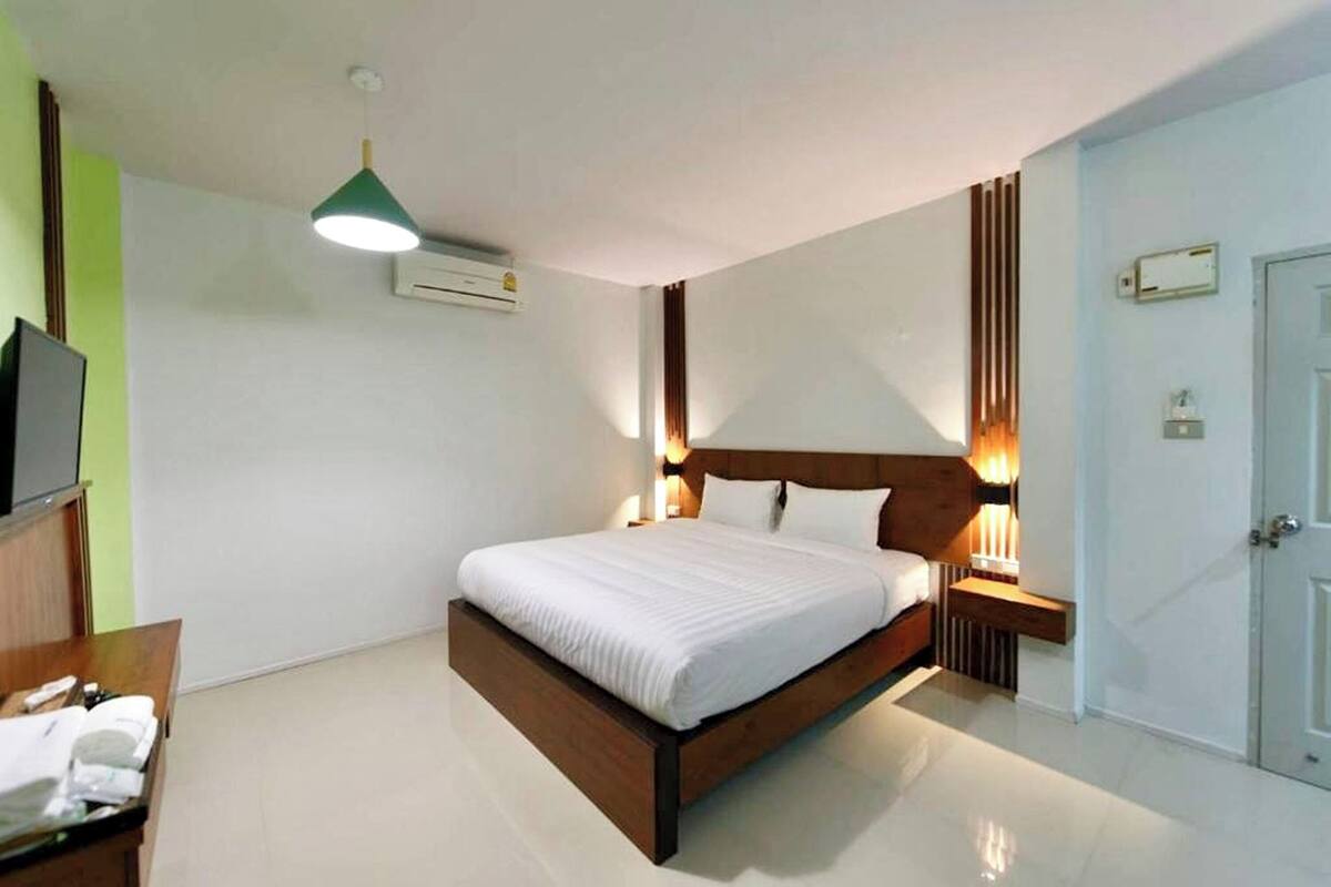Ein modernes Hotelzimmer mit einem großen Bett, Nachttischlampen, einem Flachbildfernseher und einem Holznachttisch.