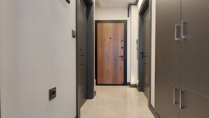 Un pasillo con una puerta de madera al final, flanqueado por armarios y un piso de color claro.
