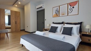 Un dormitorio moderno con una cama grande, mesitas de noche, un armario y una obra de arte en la pared.