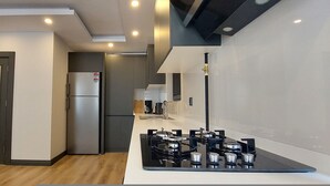 Una cocina moderna con estufa a gas integrada, refrigerador de acero inoxidable y muebles blancos.