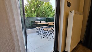A view from inside a room to an outdoor balcony with a table and chairs.